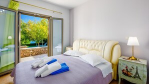 Habitación de hotel con cama, mesita de noche, lámpara y vistas a una piscina y árboles.