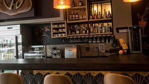 A bar area with shelves of bottles, a coffee machine, and a cash register. - ALBURA HOTEL (Pereira)
