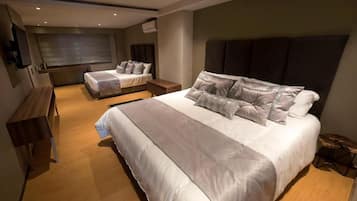 Un dormitorio moderno con una cama grande, otra más pequeña, un banco y una mesita.