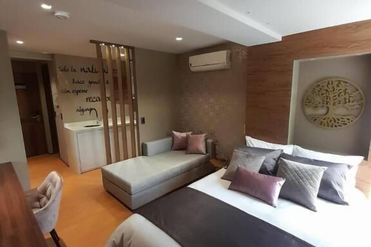 A modern bedroom with a large bed, a small sofa, and a desk.