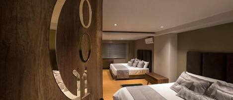 A modern bedroom with two beds, a large mirror, and a wooden accent wall.