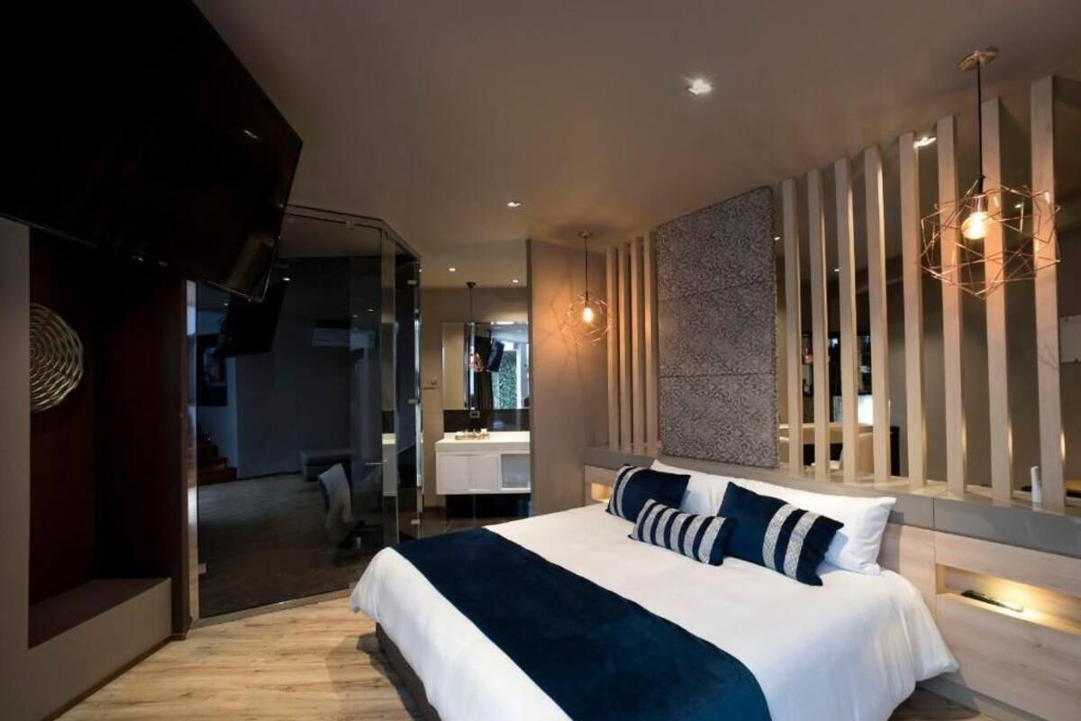 A modern bedroom with a large bed, a glass partition, and a unique light fixture.