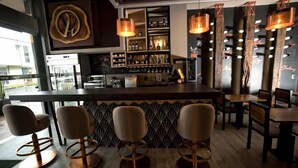 A bar area with a counter, bar stools, and hanging pendant lights. - ALBURA HOTEL (Pereira)