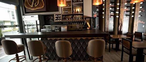 Un espace bar avec un comptoir, des tabourets de bar et des luminaires suspendus.