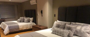 Habitación de hotel con dos camas, una mesita de noche y un teléfono en la pared.