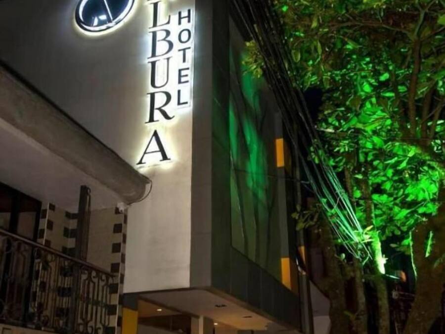 Exterior de l'Hotel Alburra amb un cartell il·luminat ben visible.