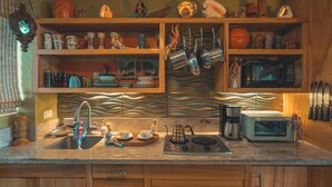 Une cuisine dotée de meubles en bois, d’un évier, d’un four à micro-ondes et de divers ustensiles de cuisine.