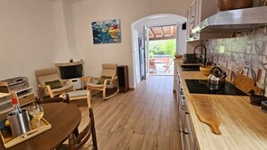 Eine moderne Küche mit Holzboden, einem Essbereich mit Tisch und Stühlen, einem Fernseher und Blick auf eine Terrasse.