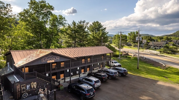 A building with a sign reading 'The Lincoln' and a parking lot with several cars.