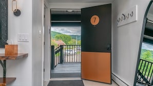 A hotel entrance with a door marked '7', a view of a parking area, and a balcony with a railing.