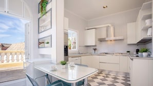 A modern kitchen with white cabinets, a glass dining table, and a checkered floor.