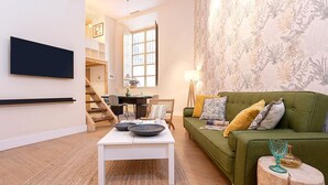 A living room with a green sofa, white coffee table, and a flat-screen TV mounted on the wall. - Charming apartment in Malaga center. San Agustin VIII (Malaga)