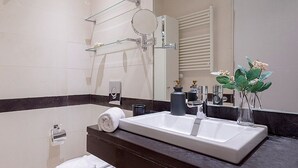 A modern bathroom with a large white sink, a glass shower enclosure, a towel rack, and a mirror. - Charming apartment in Malaga center. San Agustin VIII (Malaga)