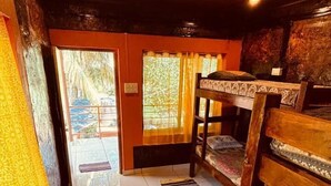 A room with a wooden bench, a patterned rug, and a view of the outdoors through a window with curtains. - Experience Gokarna - A Slow-Paced Backpackers Community (Gokarna)