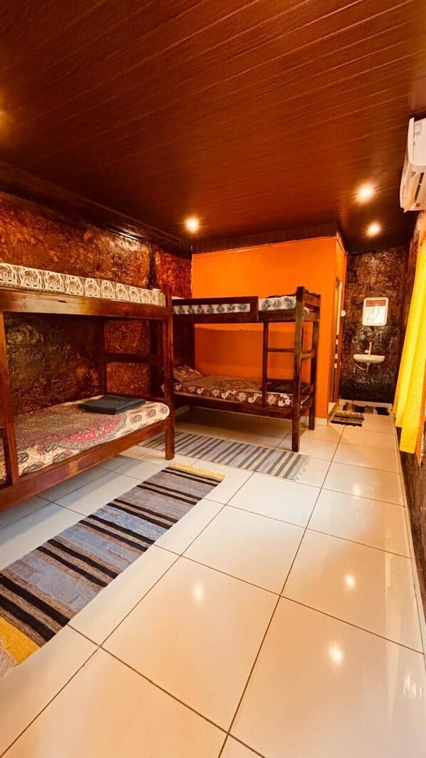 Una habitación con literas, un baño pequeño con lavamanos y piso de baldosas.