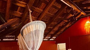 A room with a bed, a hanging light fixture, and a red wall. - Experience Gokarna - A Slow-Paced Backpackers Community (Gokarna)