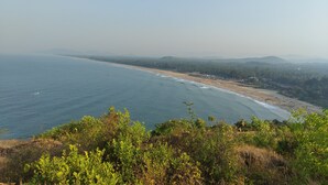 A coastal landscape with a beach, ocean, and distant hills. - Experience Gokarna - A Slow-Paced Backpackers Community (Gokarna)