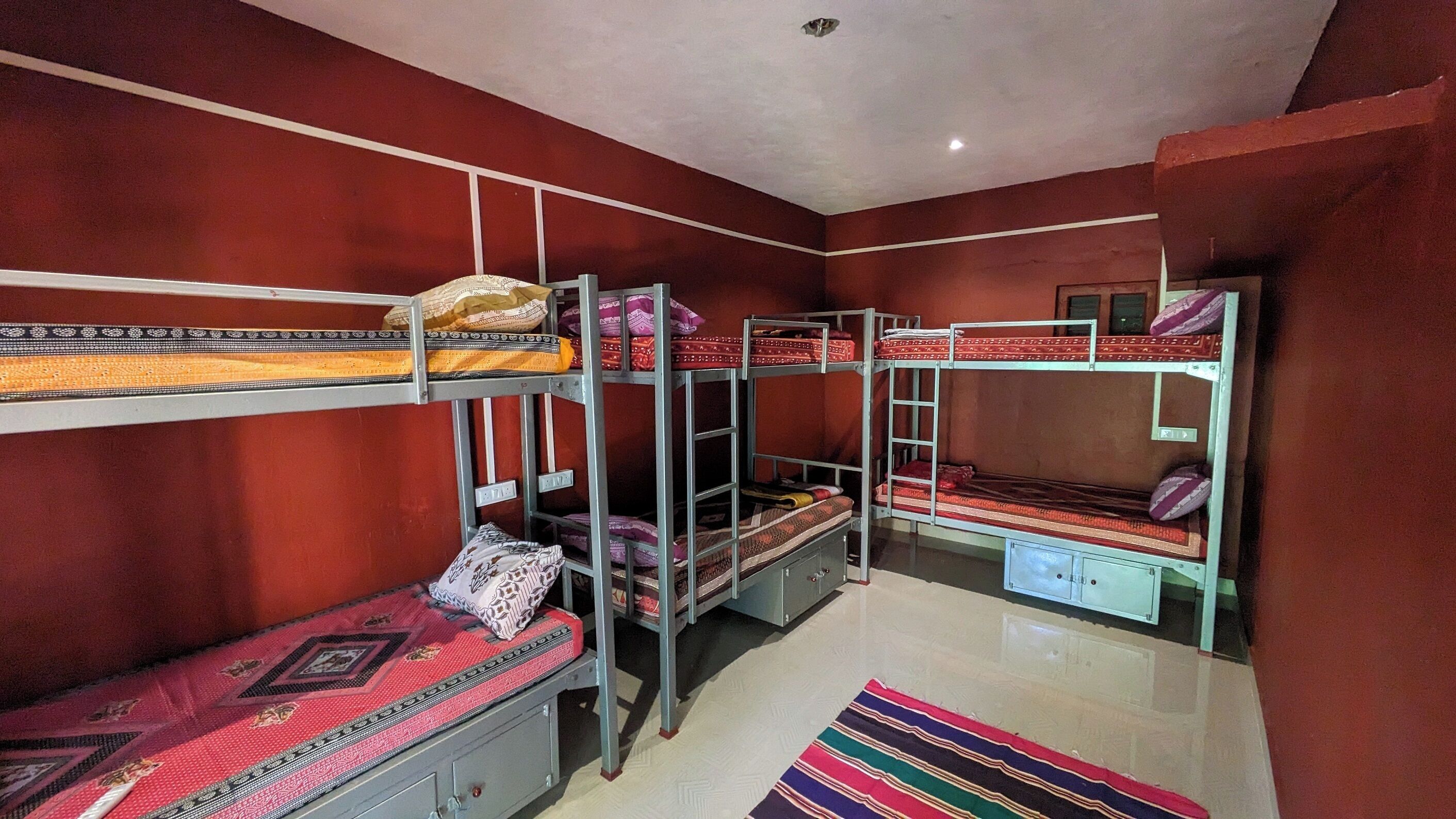 Un dormitorio con literas, un escritorio pequeño y una alfombra colorida.