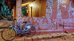 A bicycle parked against a wall with intricate white patterns and a wooden door. - Experience Gokarna - A Slow-Paced Backpackers Community (Gokarna)