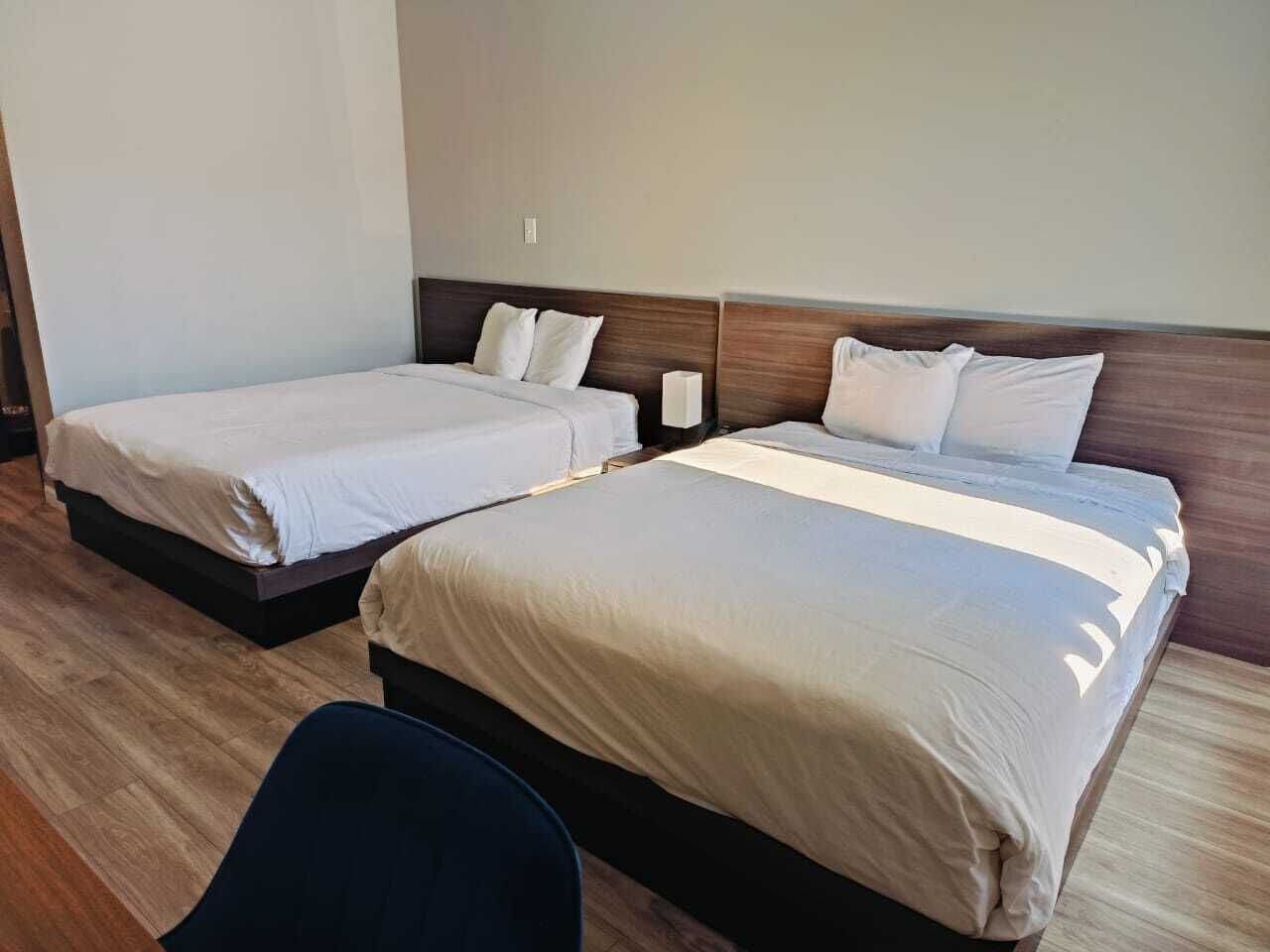 Zwei Einzelbetten mit Holz Kopfteilen und weißer Bettwäsche in einem Hotelzimmer.