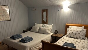 Un dormitorio con dos camas, cabeceros de madera, una mesita de noche y un cuadro enmarcado en la pared.