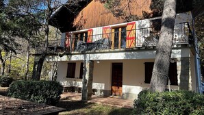 Un edificio de dos pisos con balcón, pilares de piedra y una puerta de madera.