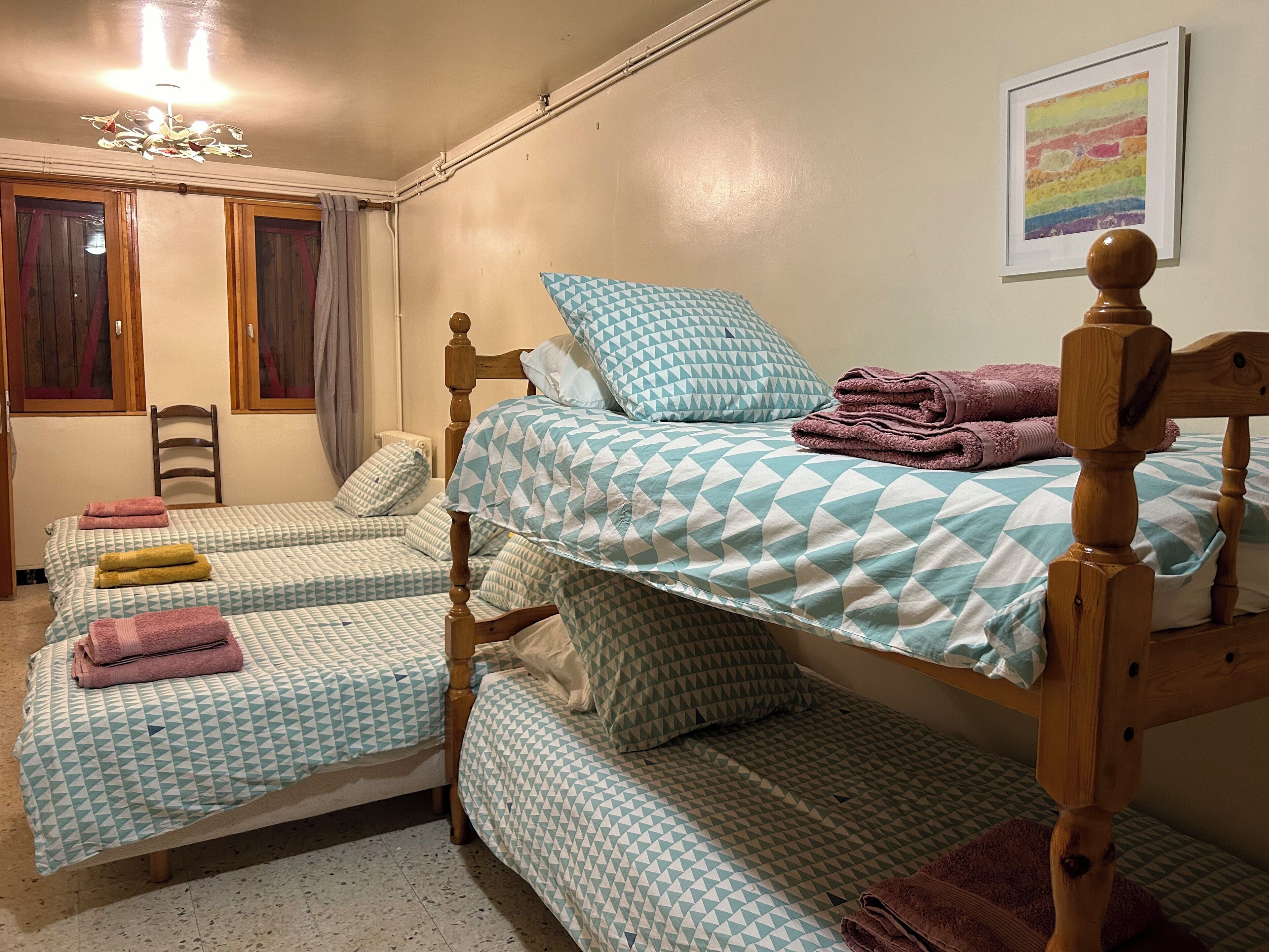 Une chambre avec deux lits simples, chacun doté d’une tête de lit en bois, et une petite chaise en bois.