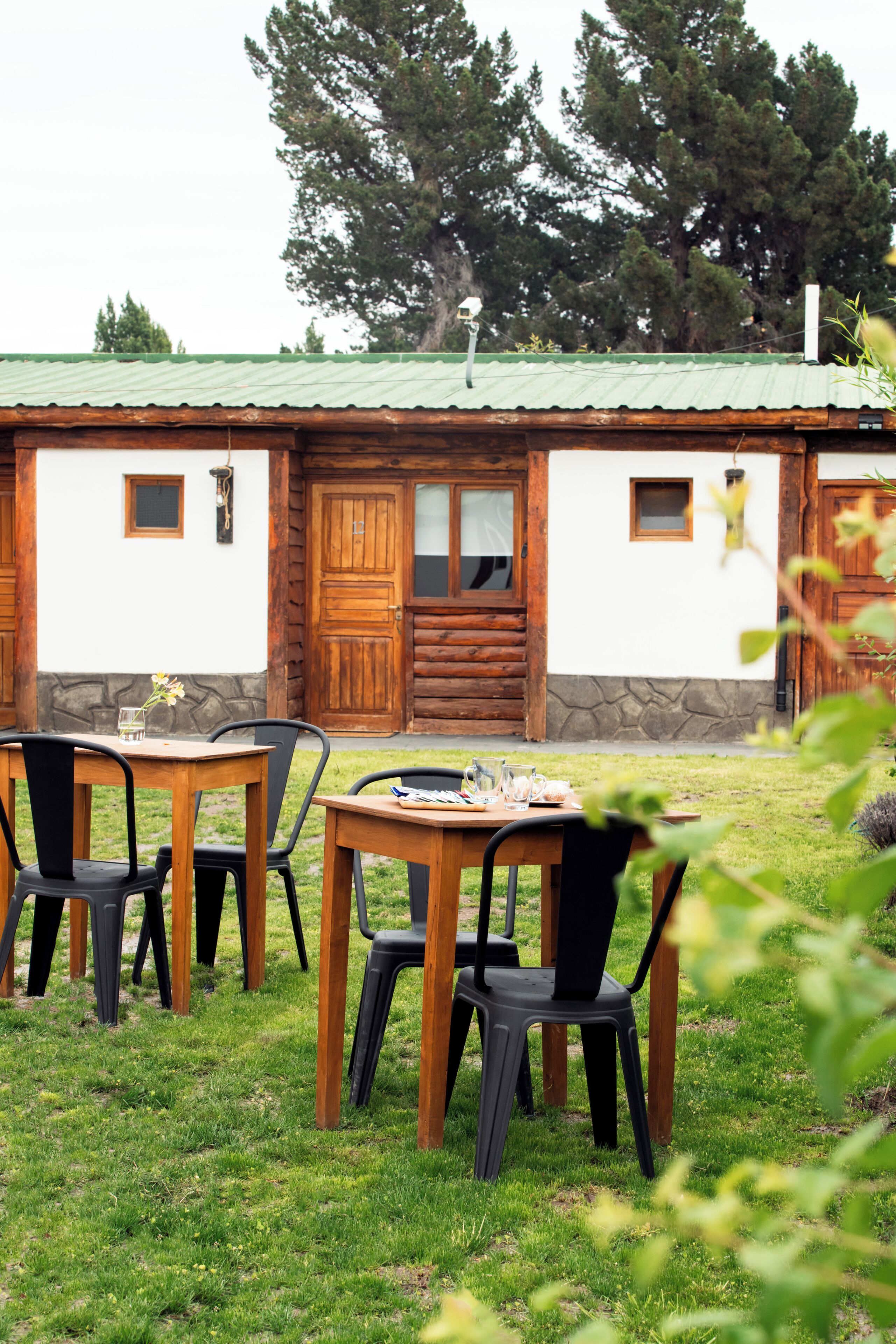 A rustic cabin with a stone foundation, wooden doors, and a green metal roof.