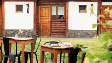 A rustic cabin with a stone foundation, wooden doors, and a green metal roof.