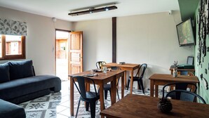 Une pièce comprenant un canapé, une table à manger en bois, des chaises, un téléviseur et un sol à motifs.