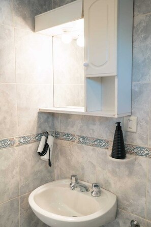 Un baño con lavamanos, espejo y perchero para toallas.