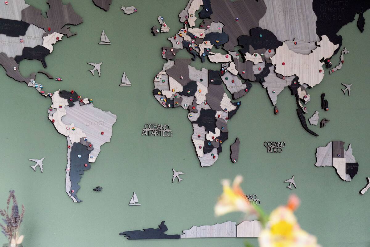 Un tavolo da pranzo con una mappa del mondo, un vaso con fiori e uno smartphone.