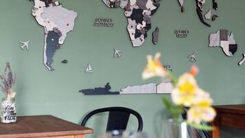 A dining table with a world map, a vase with flowers, and a smartphone.