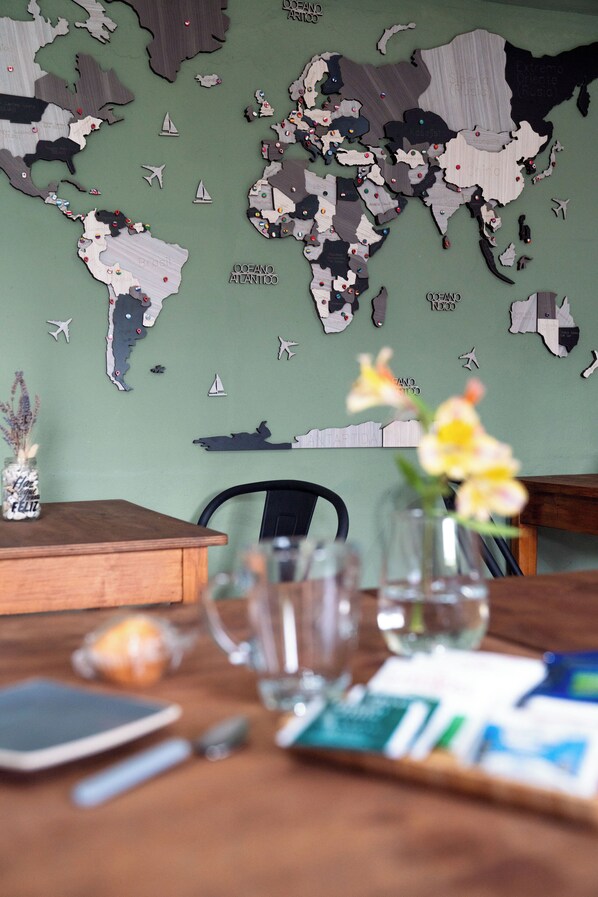 Una mesa de comedor con un mapa del mundo, un florero con flores y un teléfono inteligente.