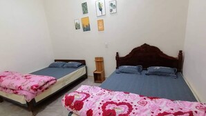 Ein Schlafzimmer mit zwei Betten, jedes mit einer anderen Bettdecke. Darüber an der Wand befinden sich Bilder.