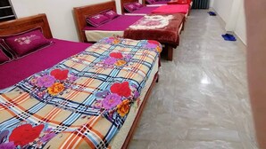 Ein Hotelzimmer mit zwei Einzelbetten, jeweils mit einem blumigen Überwurf und passenden Kissen.