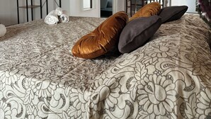 Een slaapkamer met een bed met een patroondisign, een houten nachtkastje en een kledingkast.