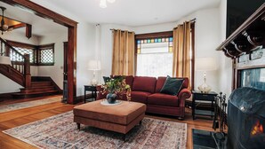 Ein Wohnzimmer mit rotem Sofa, Holzboden, Kamin und einer Treppe.
