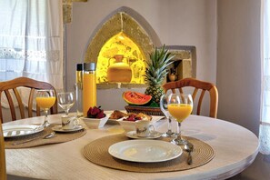 A breakfast setting with a table set for two, featuring plates, glasses, and a bowl of fruit. - Apartments Panethimos (Platanias)