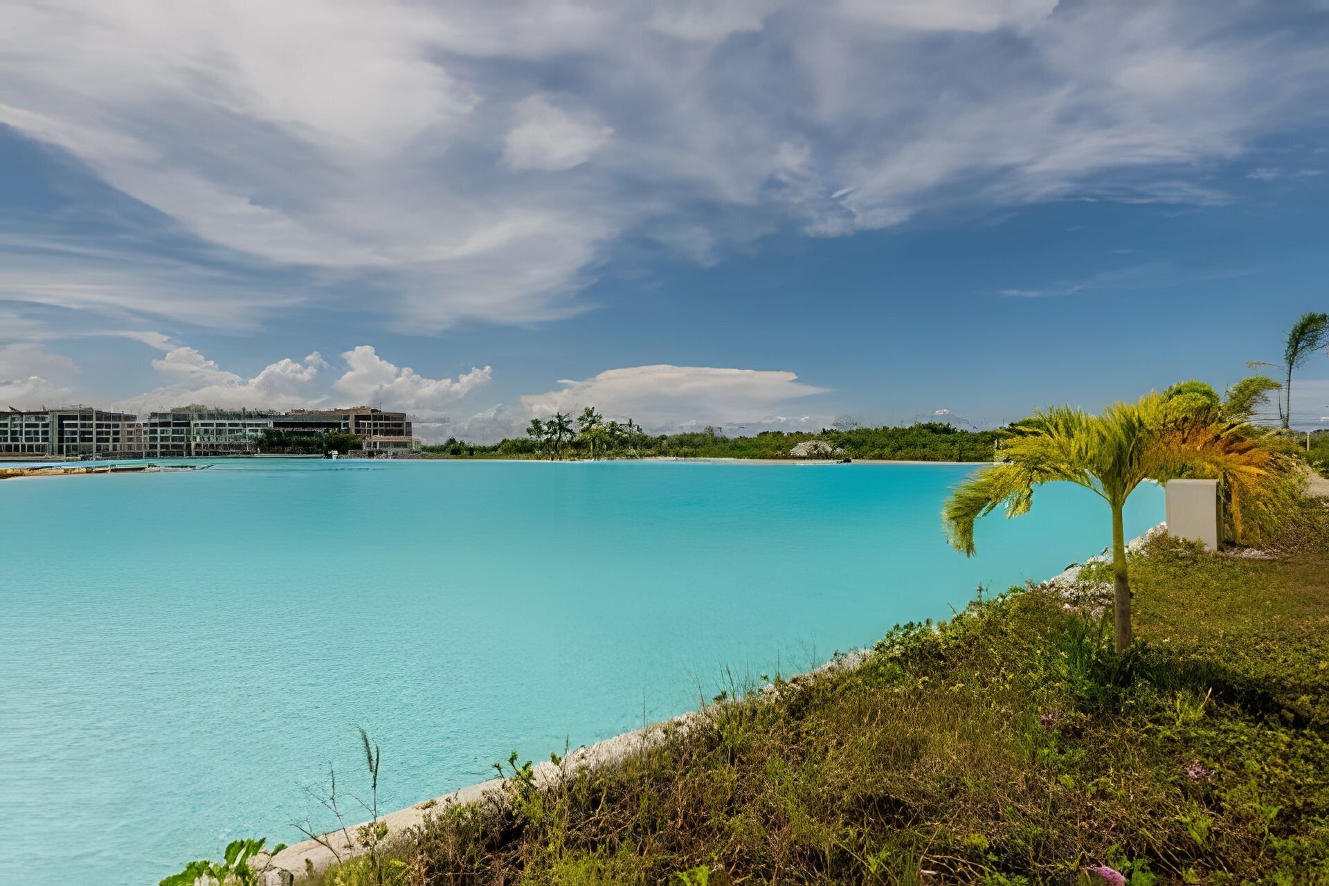 A resort with a large pool, palm trees, and a clear sky.