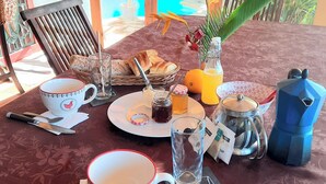 A table set with breakfast items, a coffee pot, and a view of a swimming pool. - Ideally located, independent room with swimming pool (Le Marin)