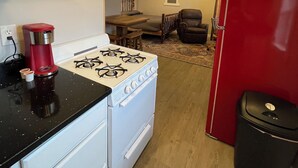 Cocina compacta con estufa, un refrigerador rojo y comedor con mesa y sillas.