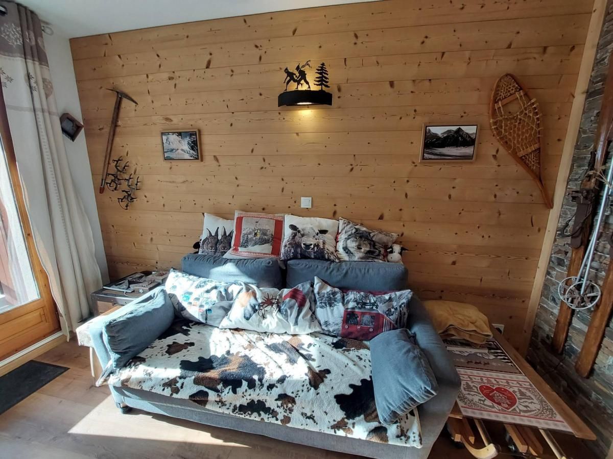 A cozy room with a wooden wall, a sofa with patterned cushions, and a small table with a decorative item.