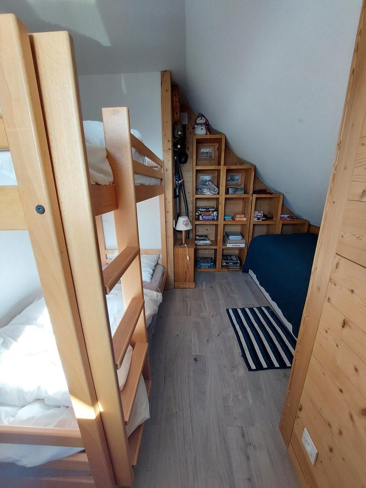 Una habitación pequeña con literas, un escritorio y una estantería.