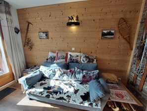 A cozy room with a wooden wall, a sofa with patterned cushions, and a small table with a decorative item.