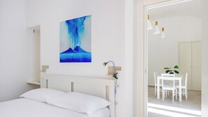 Ein Schlafzimmer mit Bett, einer Wanddusche, einer Essecke mit Tisch und Stühlen sowie einem Bild an der Wand.