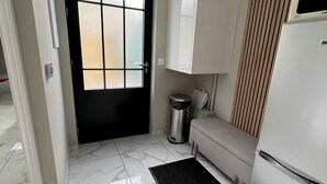 A modern kitchen with a marble floor, a black door, a white refrigerator, and a beige sofa. - House in Creteil near Paris (creteil)