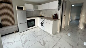 A modern kitchen with white cabinetry, a built-in oven, a washing machine, and a microwave. - House in Creteil near Paris (creteil)