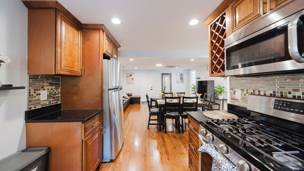 A modern kitchen with wooden cabinets, a stainless steel refrigerator, a built-in microwave, and a gas stove. - Cozy 2BR Quincy Hideout • Pet-Friendly • Wollaston Beach & Red Line 74L (Quincy)