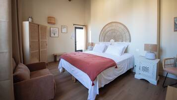 Un dormitorio con cama, sofá, mesita de noche y silla.